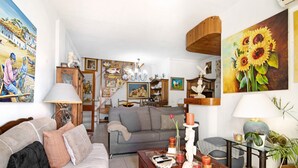 A living room with a sofa, a coffee table, and a painting of sunflowers.
