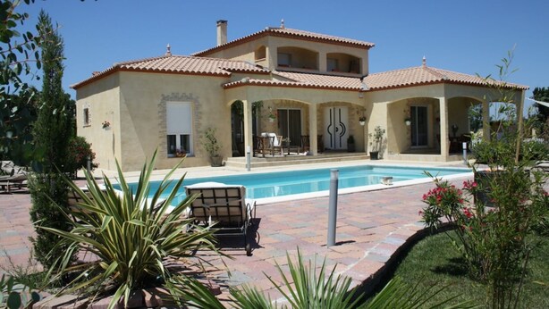 Una casa de dos pisos con piscina, zona de estar exterior y jardín.