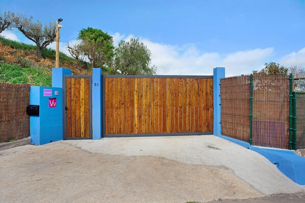 Una entrada protegida con puerta de madera, buzón y pared azul.