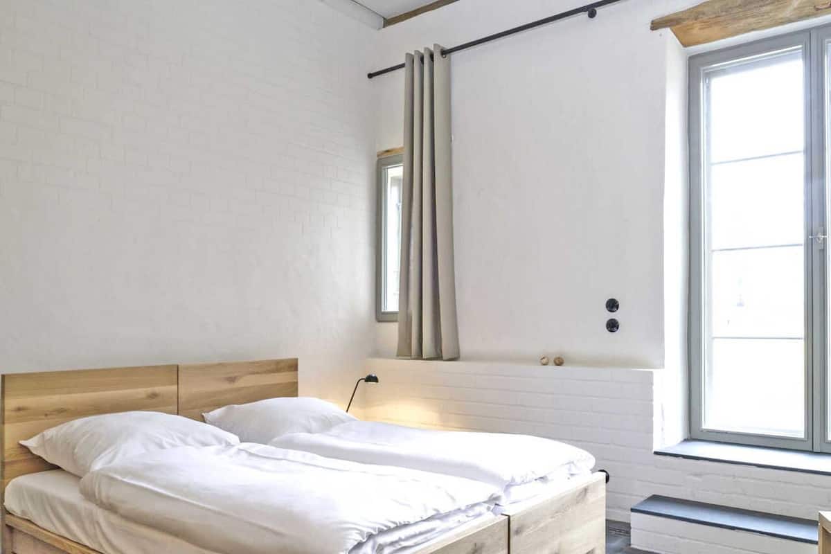 Une chambre à coucher avec un lit, une fenêtre et un miroir fixé au mur.