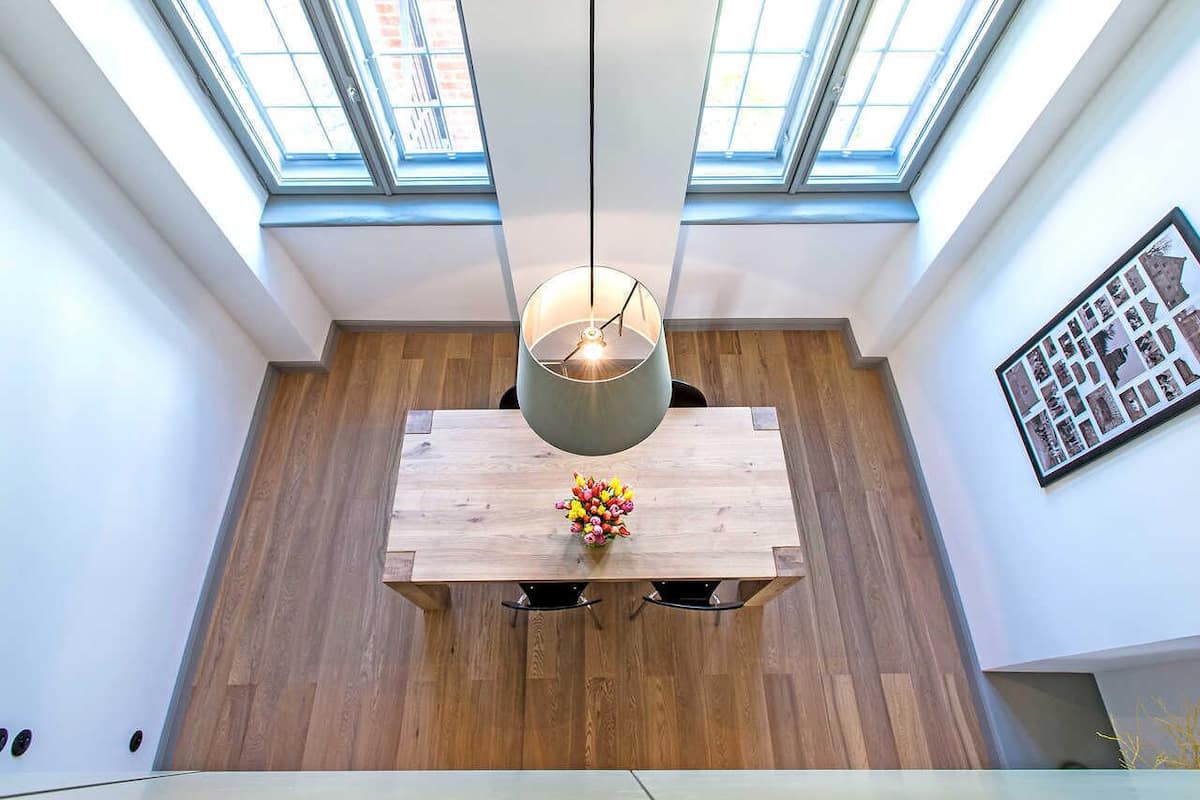 Un espace repas avec une table en bois, un luminaire suspendu et des fenêtres de toit.