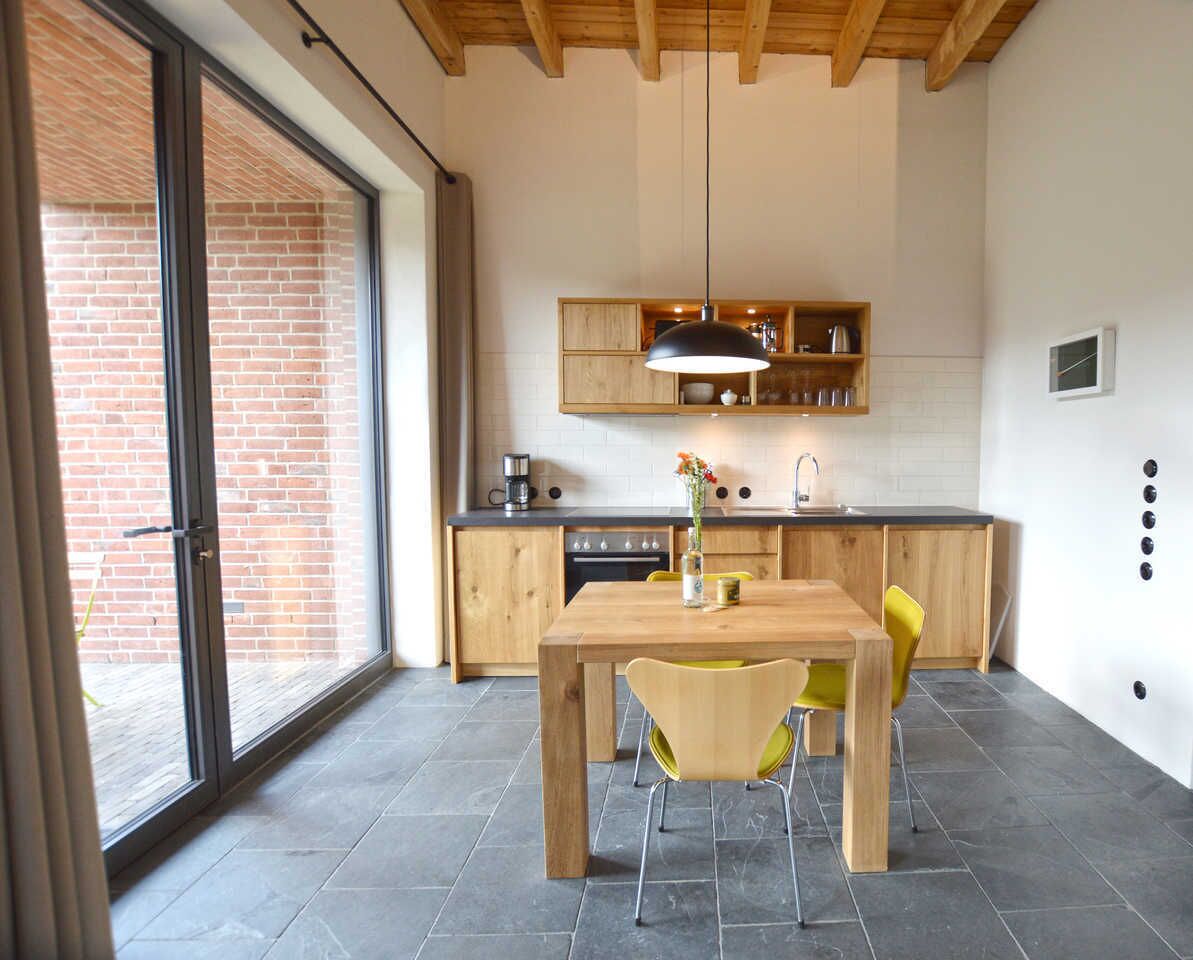 Een moderne keuken met houten kastjes, een eettafel en stoelen.