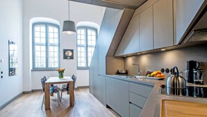 A modern kitchen with a dining area, large windows, and a view of the city.