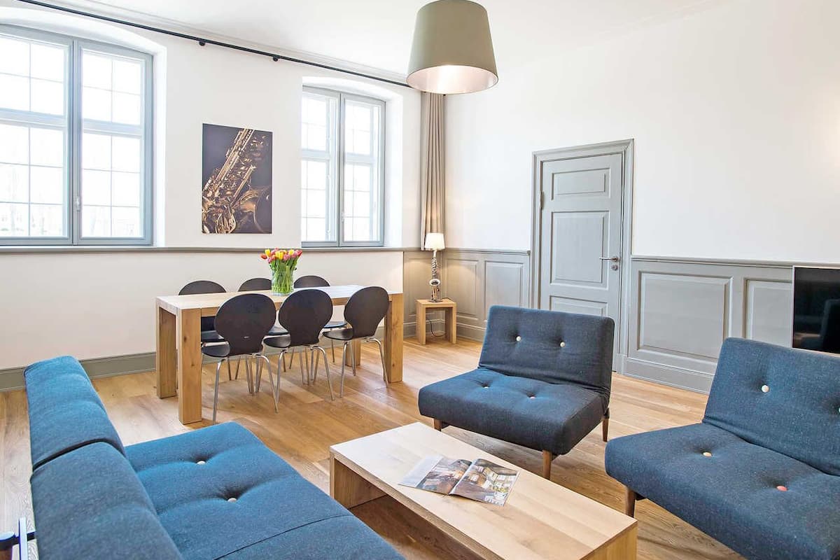 Un salon moderne comprenant un canapé, des fauteuils, une table basse et un coin repas avec des chaises et une table.