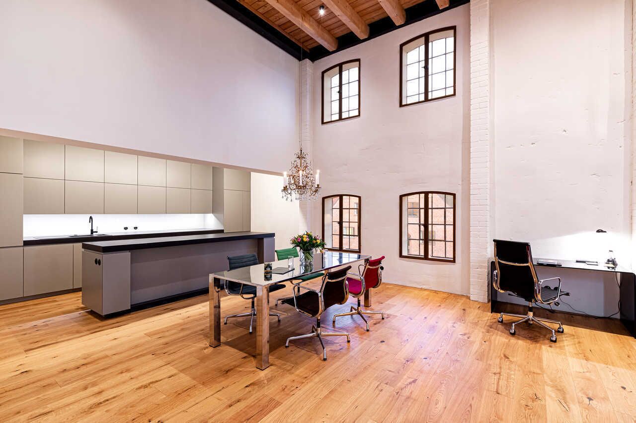 Una cocina moderna con una isla central, suelo de madera y un comedor con mesa y sillas.