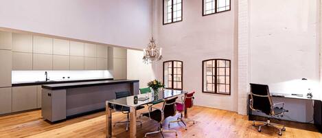 Una cocina moderna con una isla central, suelo de madera y un comedor con mesa y sillas.