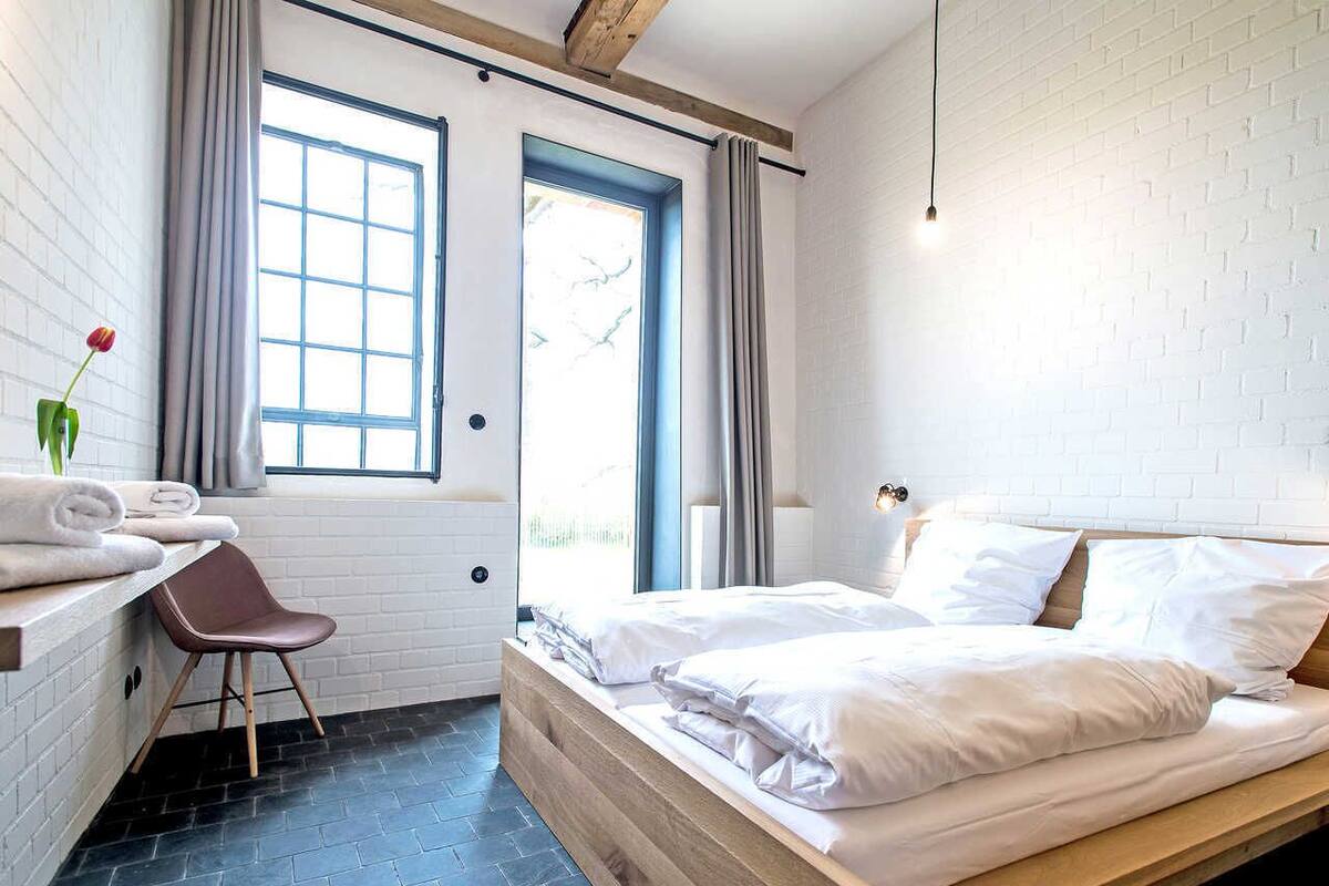 Une chambre moderne avec un lit, une chaise, une fenêtre et un porte-serviettes.