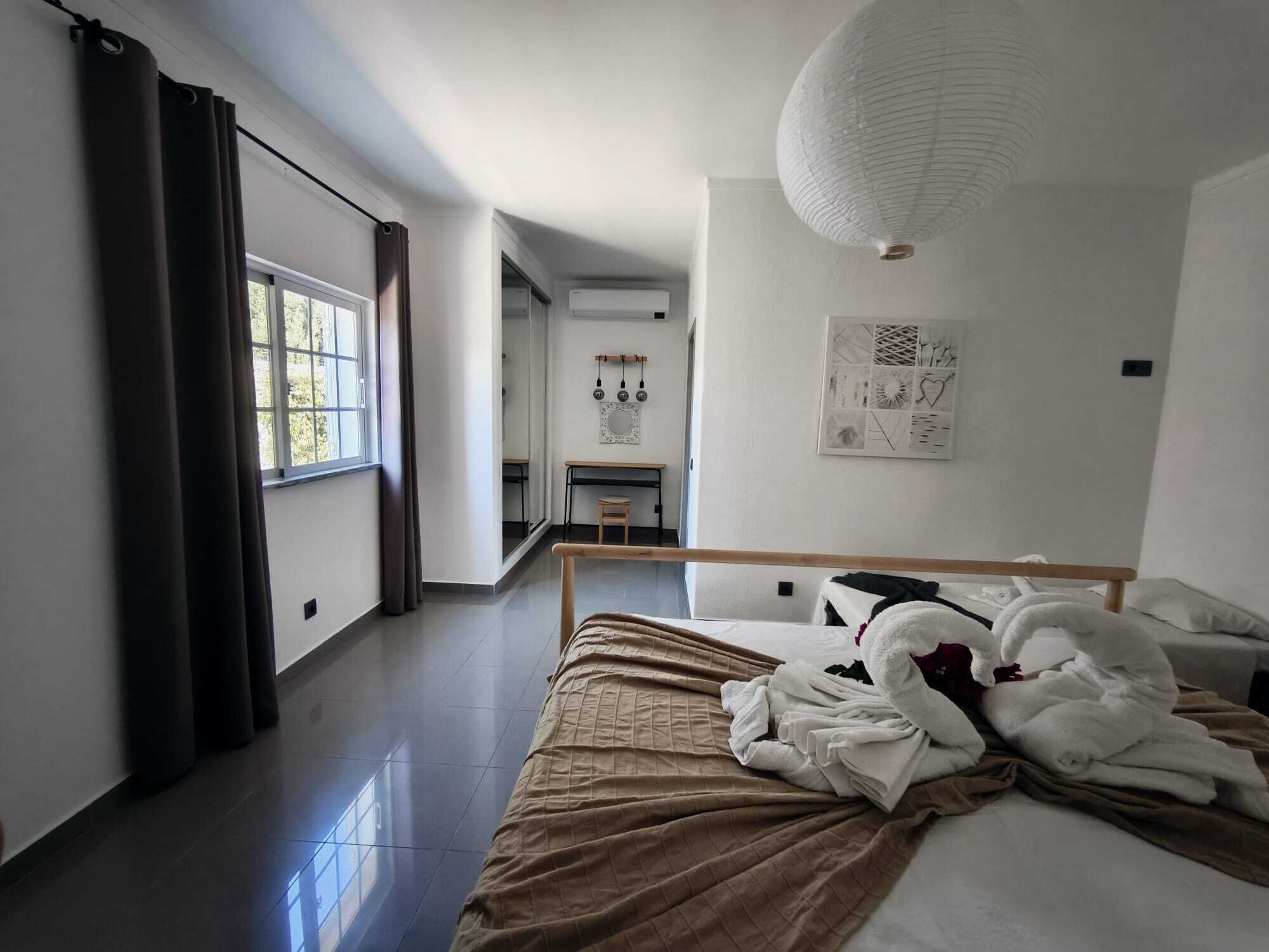 A modern hotel room with a large bed, a desk, and a view of the city.