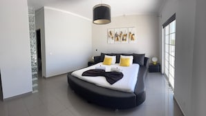 A modern bedroom with a curved bed, a large window, and a pendant light. - PRIVATE VILLA WITH POOL IN THE ALGARVE AT OLHAO NEAR FARO (OLHAO)