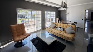 A modern living room with a sofa, armchair, and a glass coffee table. - PRIVATE VILLA WITH POOL IN THE ALGARVE AT OLHAO NEAR FARO (OLHAO)
