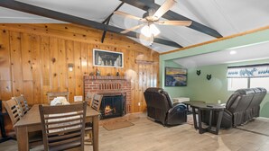 Ein gemütliches Wohnzimmer mit Kamin, Holzwänden und Deckenventilator.