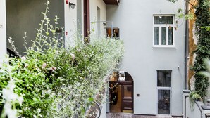 A narrow alleyway with a brick floor, a wooden door, and a small table with chairs. - Aparthotel Old Town (Kraków)