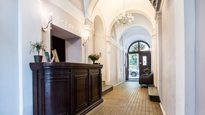 A reception area with a dark wood reception desk, a chandelier, and a tiled floor. - Aparthotel Old Town (Kraków)