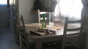 Ein Essbereich mit Tisch und Stühlen, einer Olivenölflasche und einem Glas Wasser.