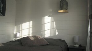 Ein Schlafzimmer mit einem Bett, einem Nachttisch, einer Lampe und einer Statue an der Wand.