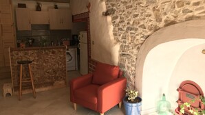 Ein gemütliches Wohnzimmer mit einem roten Sessel, einer Steinwand und einer Küche im Hintergrund.