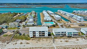 A coastal residential area with houses along a waterway, a swimming pool, and a beach.