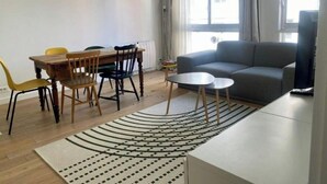 Un soggiorno moderno con un divano grigio, un tavolo da pranzo in legno e sedie gialle.