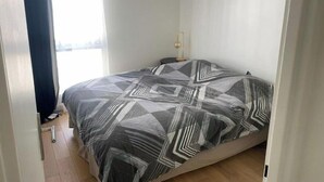 Una camera da letto con un letto, un comodino, una lampada e una finestra con tende.