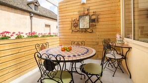 A wooden deck with a round table and chairs, a decorative wall, and a window. - BSH - Beaune Rousseau - Parking included (Beaune)