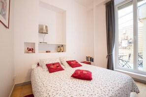 A bedroom with a bed, a bedside table, a lamp, and a window with a view of the outside. - BSH - Beaune Rousseau - Parking included (Beaune)