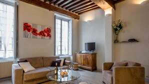 A living room with a sofa, armchair, glass coffee table, and a television on a wooden cabinet. - BSH - Beaune Rousseau - Parking included (Beaune)