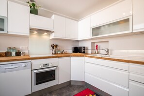 A modern kitchen with white cabinetry, a wooden countertop, a built-in microwave, and a stainless steel oven. - BSH - Beaune Rousseau - Parking included (Beaune)