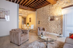 A cozy living room with a stone wall, two sofas, a glass coffee table, and a dining area in the background. - BSH - Beaune Rousseau - Parking included (Beaune)