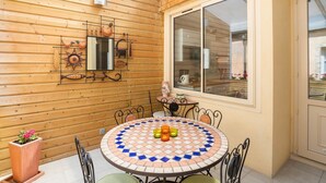 Una habitación con paneles de madera, una mesa redonda y sillas, un ventanal grande y un espejo colgado en la pared.