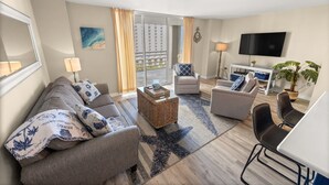 Ein modernes Wohnzimmer mit einer Couch, Sesseln, einem Couchtisch und einem Fernseher.