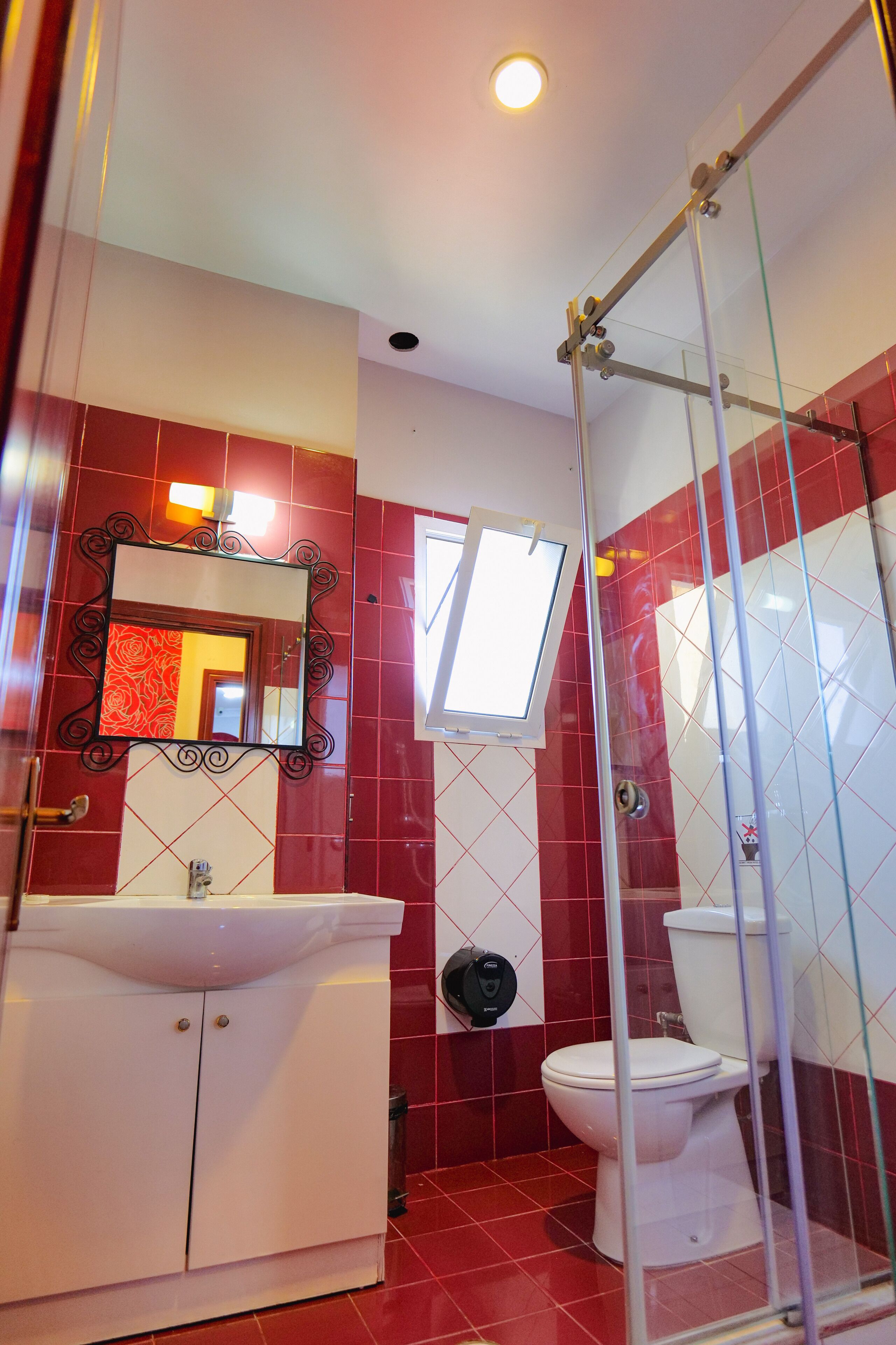 Ein Badezimmer mit Duschkabine aus Glas, einem weißen Waschbecken und einer Toilette.