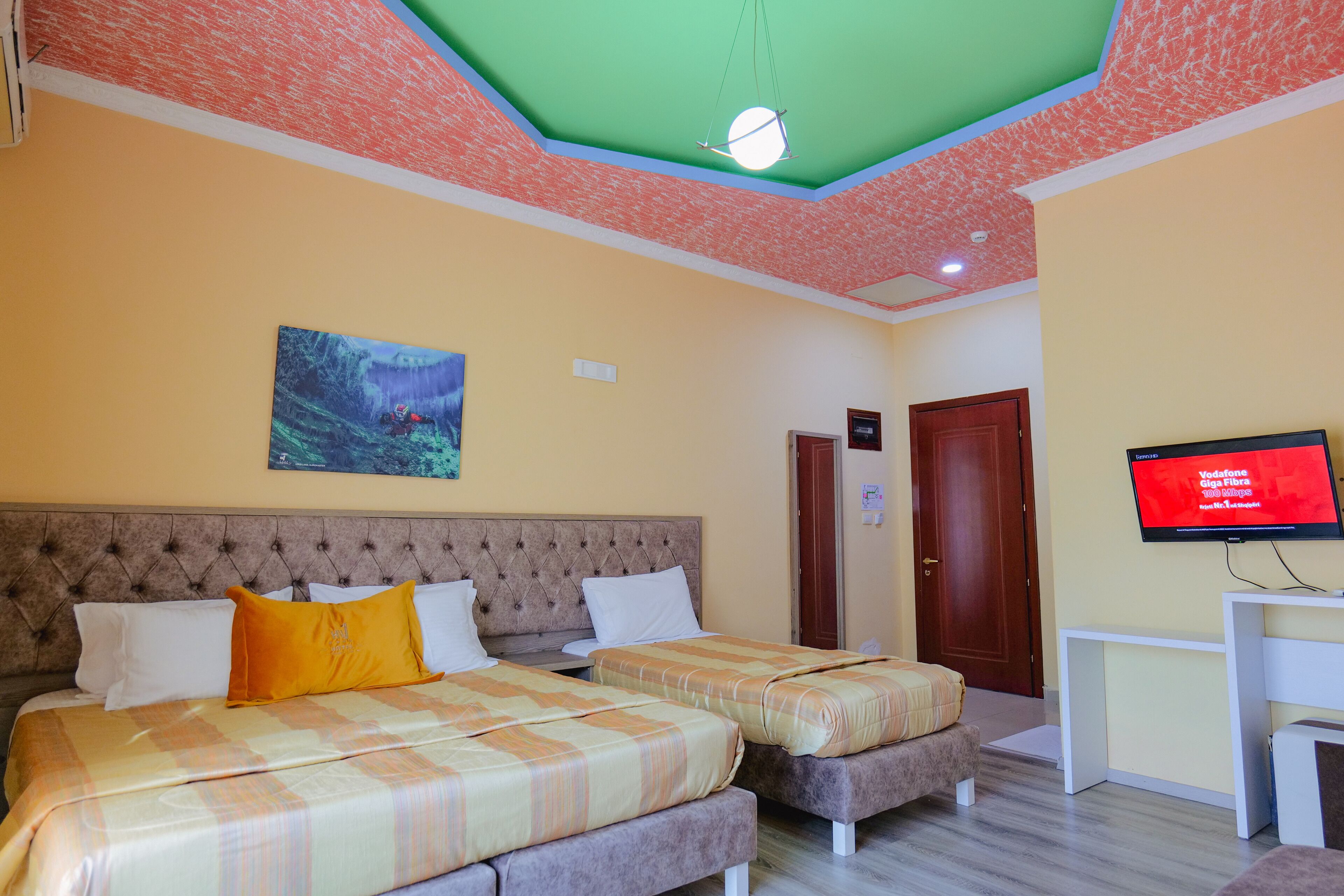 Une chambre d’hôtel avec deux lits, une télévision et un plafond au design original.