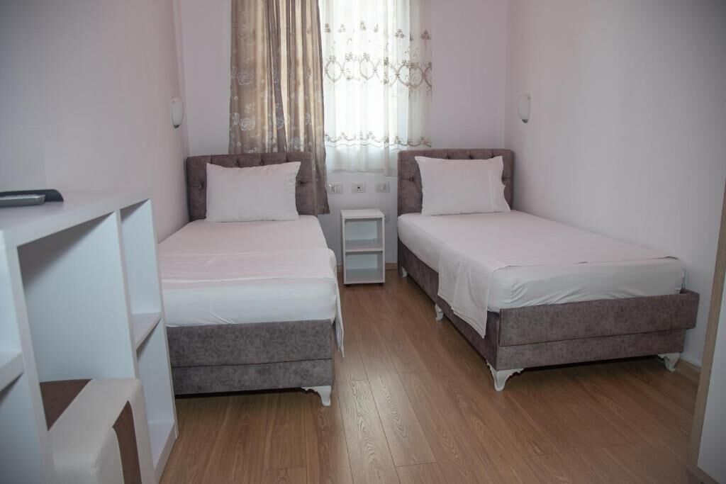 Een kamer met twee eenpersoonsbedden, een klein tafeltje en een kledingkast.