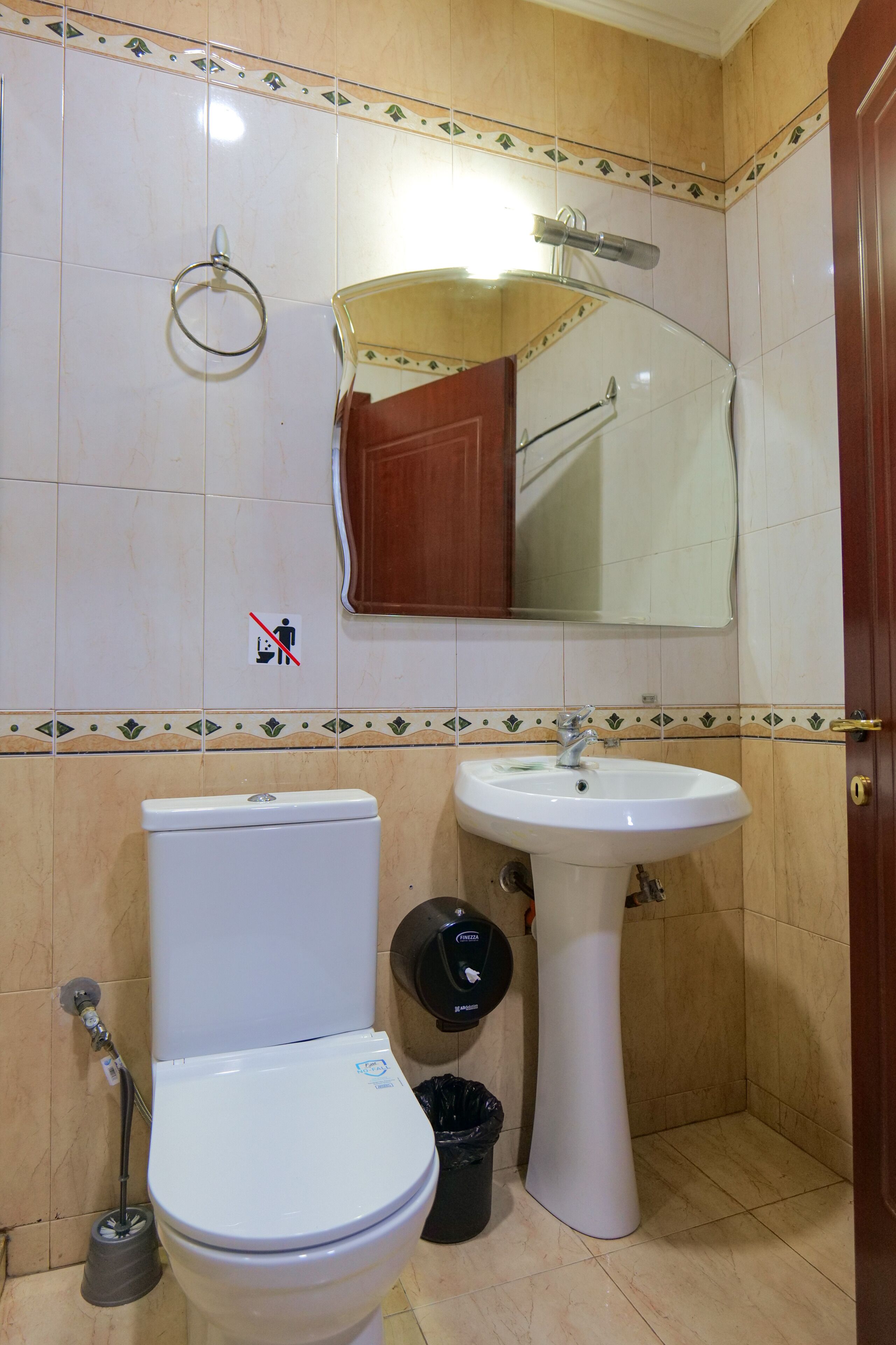 A bathroom with a toilet, sink, and mirror.