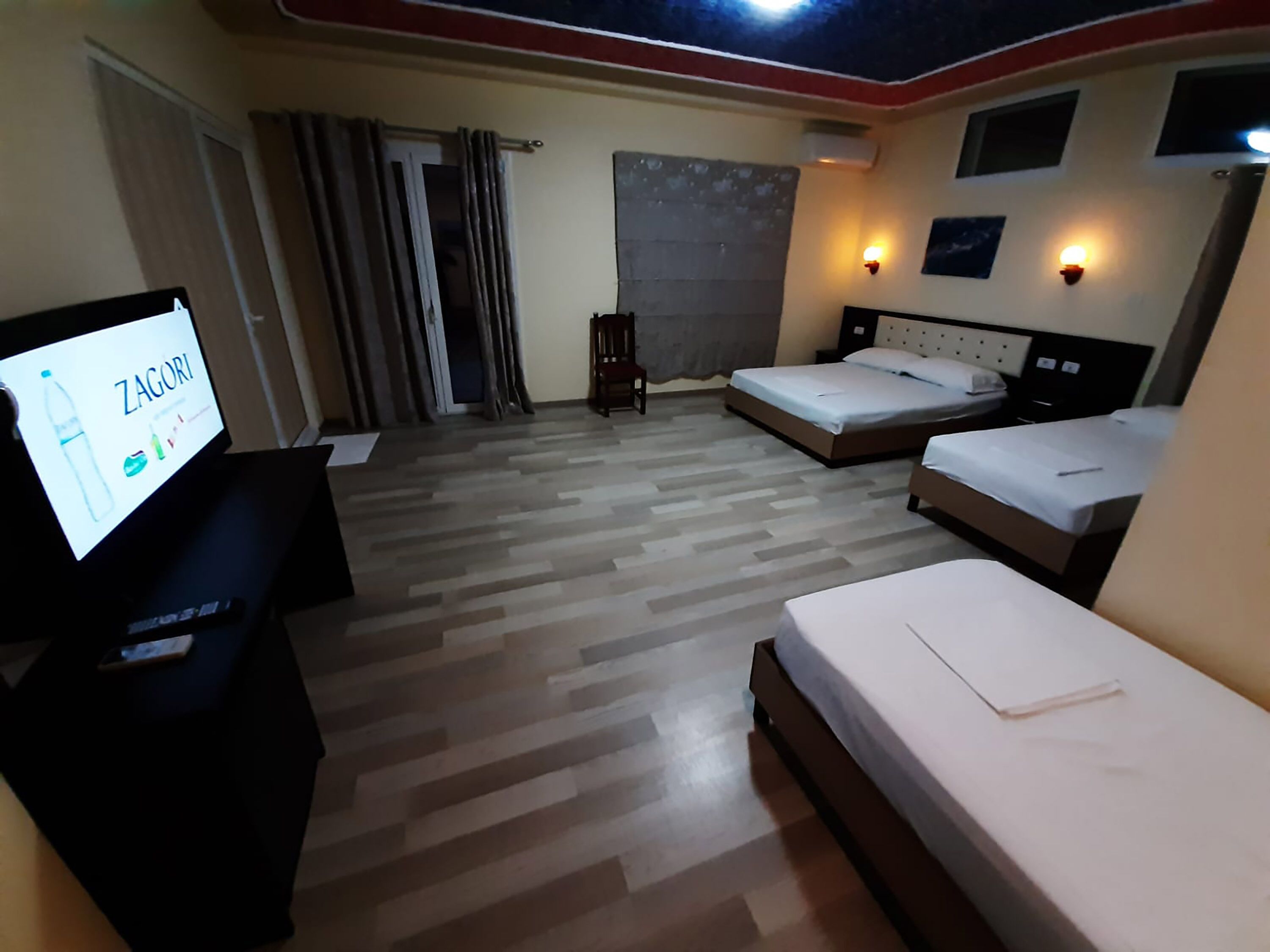 A hotel room with three beds, a TV, and a small table.