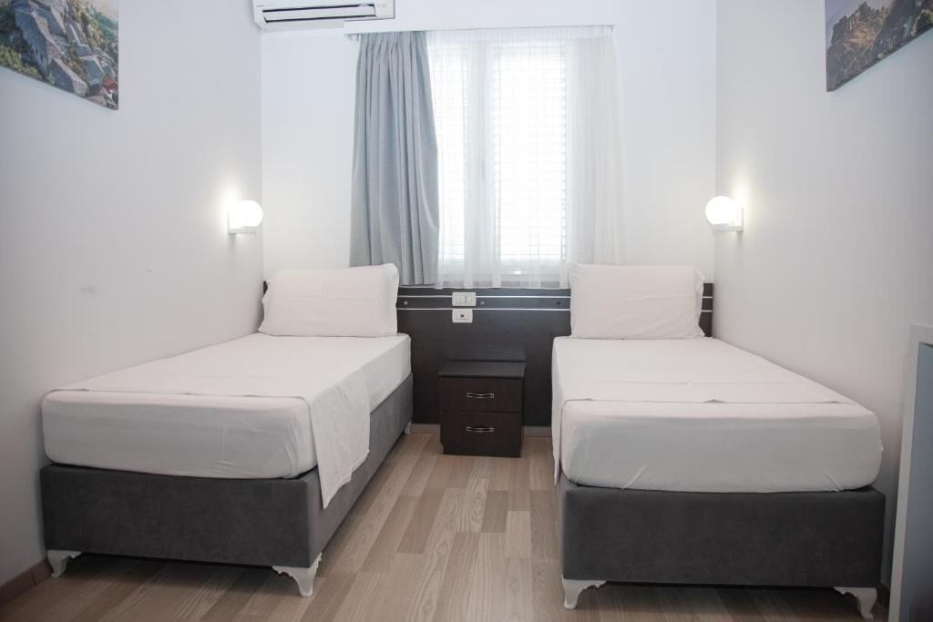 A twin room with two beds, a desk, and a small dresser.