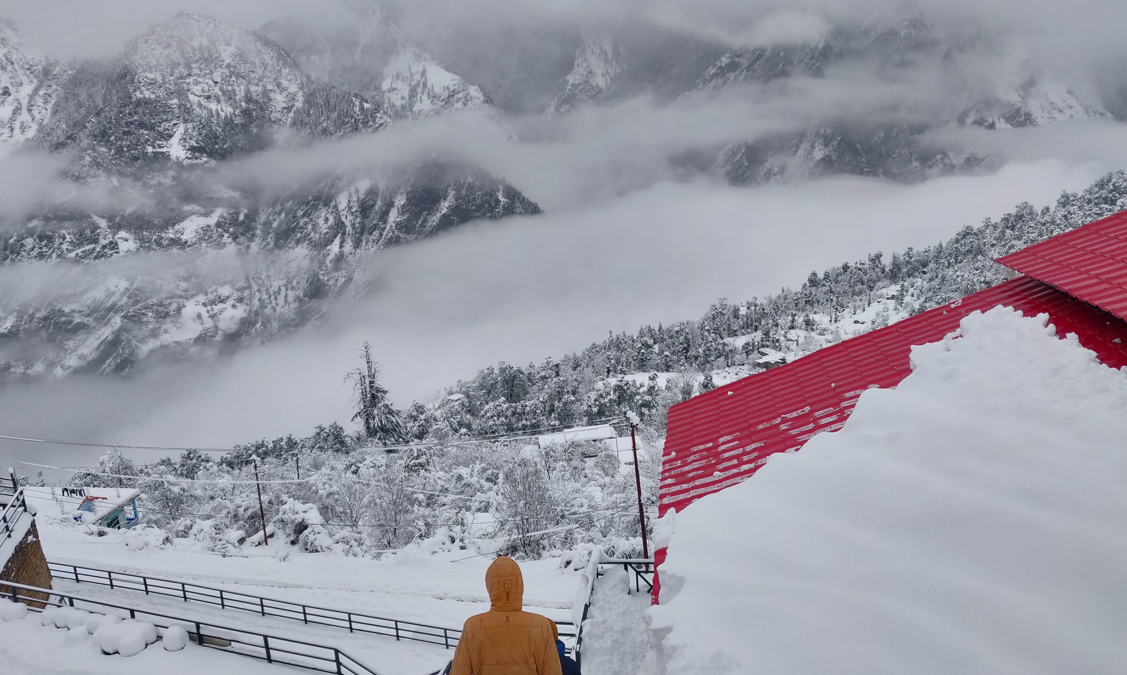 A snowy mountain landscape with a red-roofed building in the foreground.