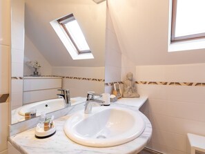 Un baño moderno con tragaluz, un espejo grande y una estatua de Buda.
