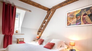 A bedroom with a sloped ceiling, a wooden ladder, a bed with white and red bedding, a nightstand with a lamp, and a painting on the wall. - BSH - Beaune Saint Etienne - Parking included (Beaune)