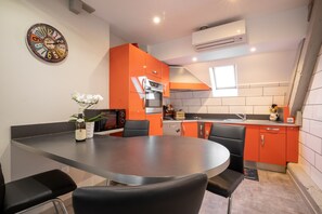 A modern kitchen with a round table, black chairs, and orange cabinetry.