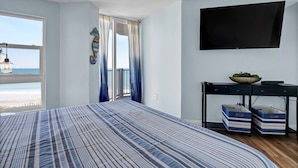 Un dormitorio con cama, televisión, escritorio y vistas a la playa.