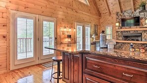 Un interior de madera con una isla de cocina, taburetes de bar y una chimenea de piedra.