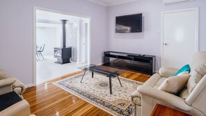 Un salon moderne avec une cheminée, un téléviseur fixé au mur et un ventilateur de plafond.