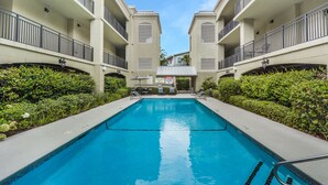 A swimming pool with a view of a building with balconies and a clear sky. - Salt Therapy! Large Studio Unit w/ extra bedroom (St. Simons Island)