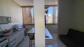 Cozinha compacta com micro-ondas, pia e área de refeições.