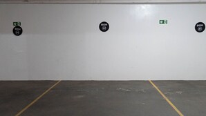 A parking garage with marked parking spaces and emergency exit signs. - CONDOMÍNIO SONHARE - 102 (Anapolis)