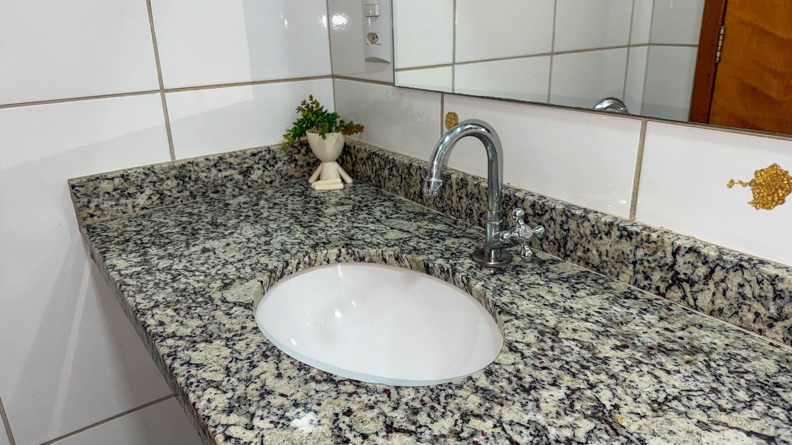 A bathroom with a granite countertop, a white sink, and a mirror.