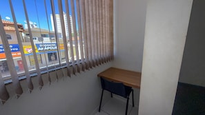 A corner room with a window, a wooden desk, and a chair. - CONDOMÍNIO SONHARE - 102 (Anapolis)