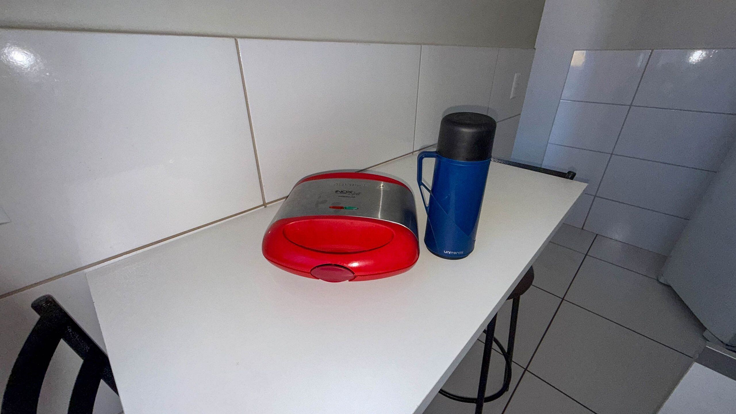 A kitchen counter with a red toaster and a blue thermos.