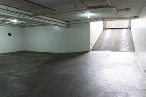 Uma garagem com piso de concreto, teto inclinado e uma janela na parede direita.